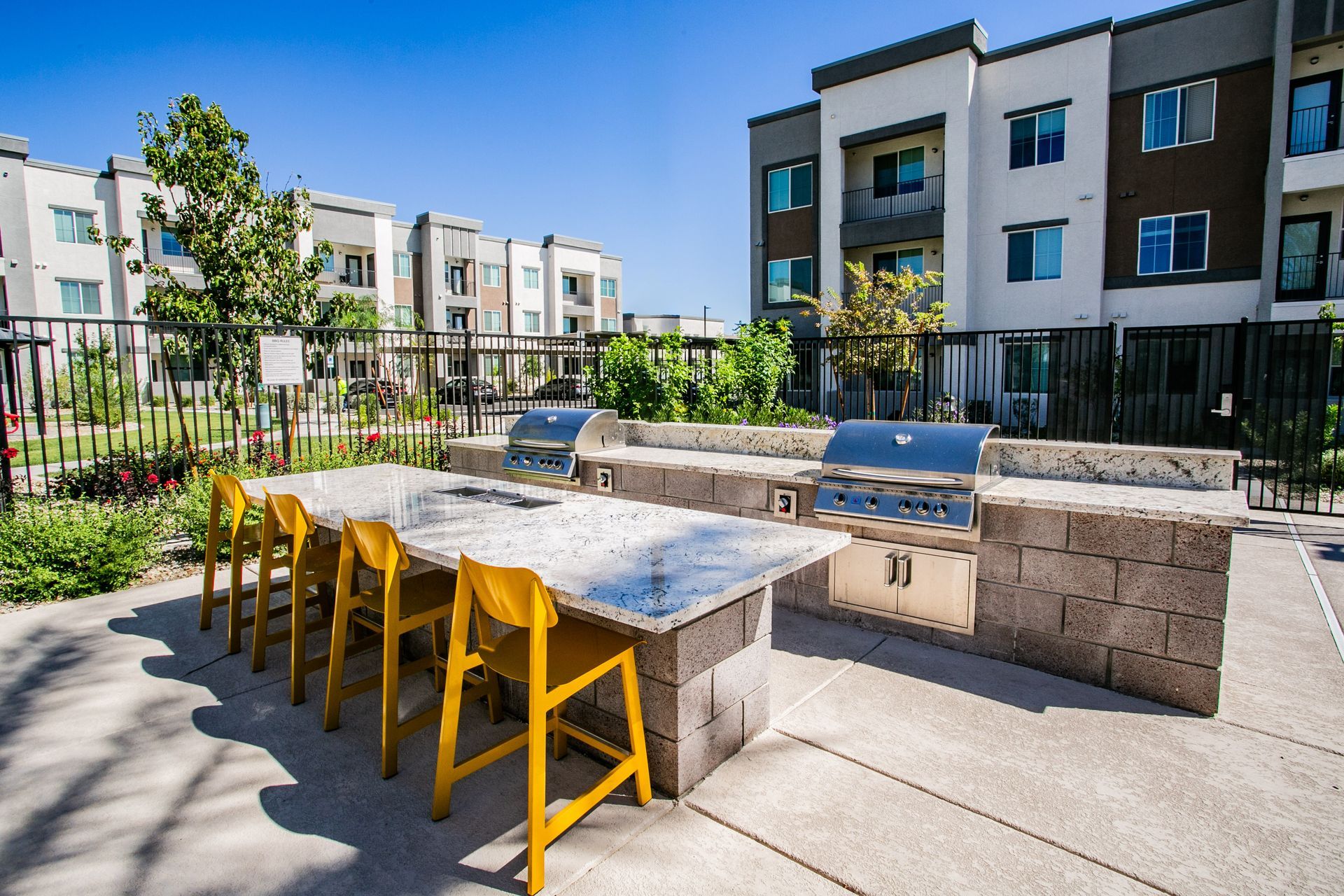 A patio with a table and chairs and a grill in front of a building.