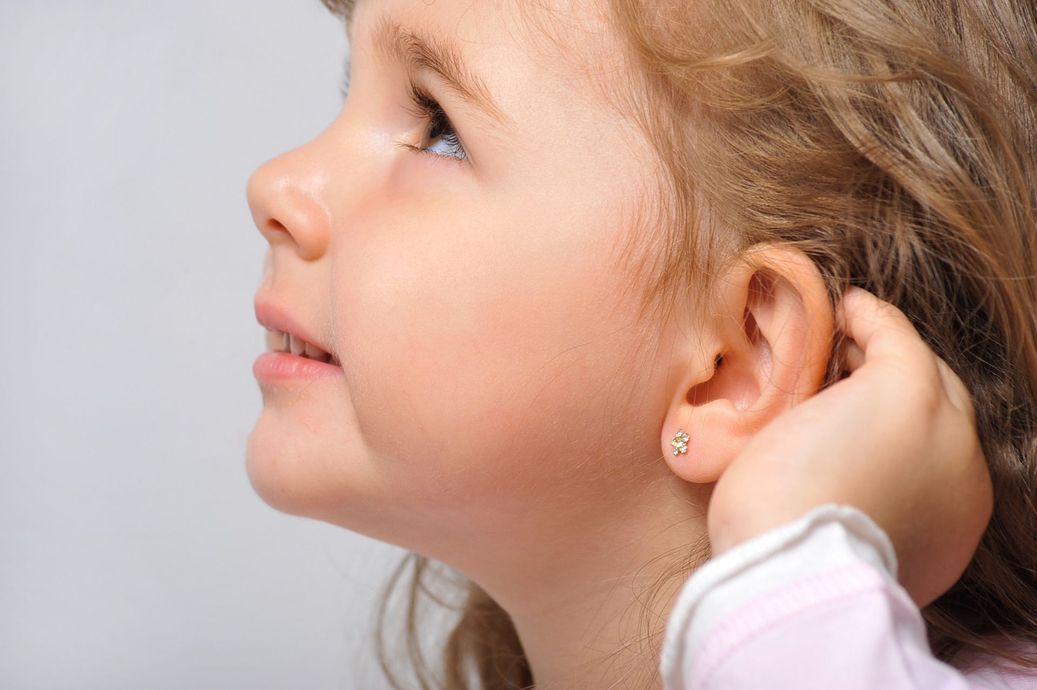 young blonde child showing pierced ear