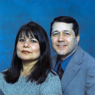 A man and woman posing for a picture with a blue background