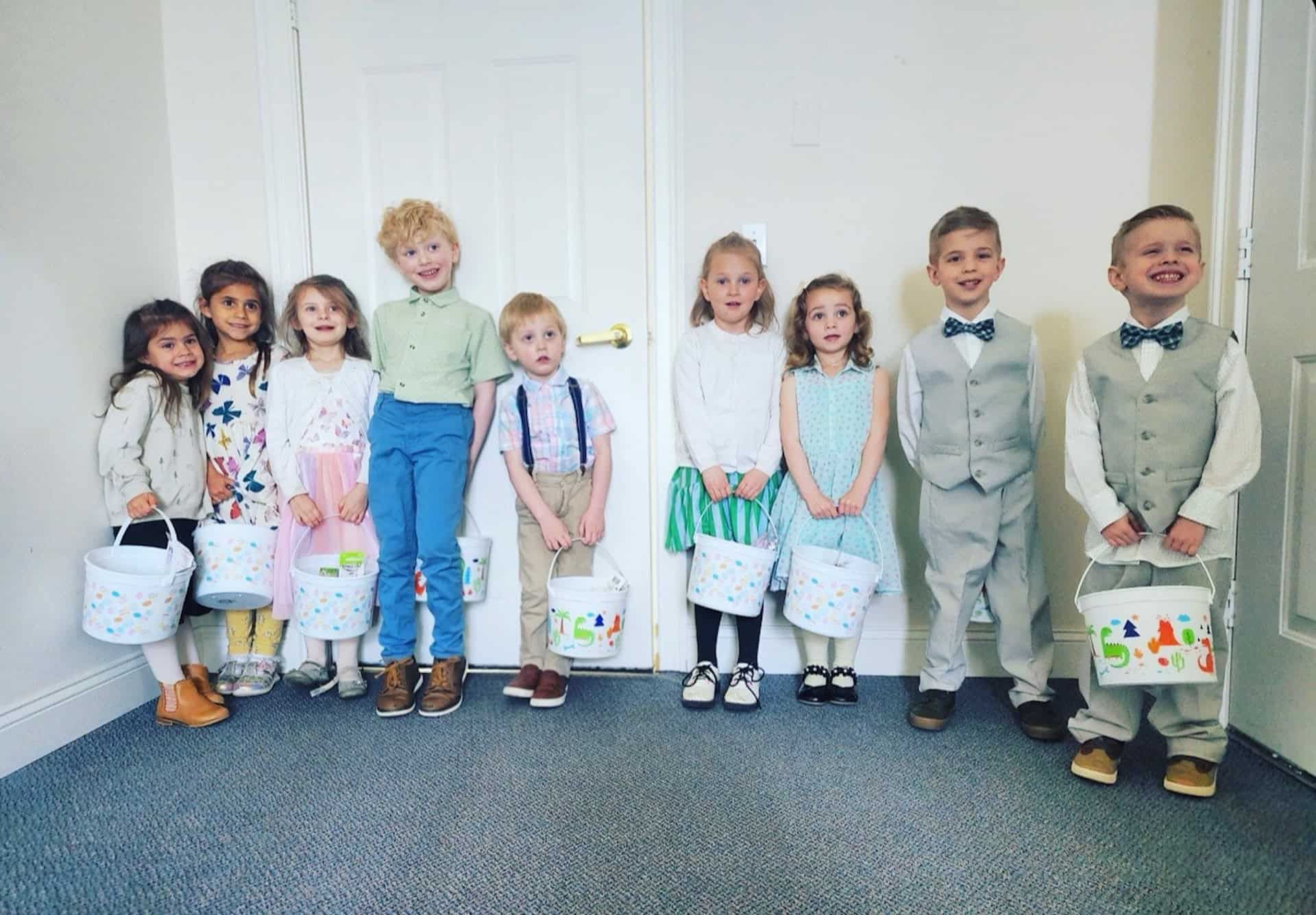 A group of children standing next to each other in a room holding buckets.