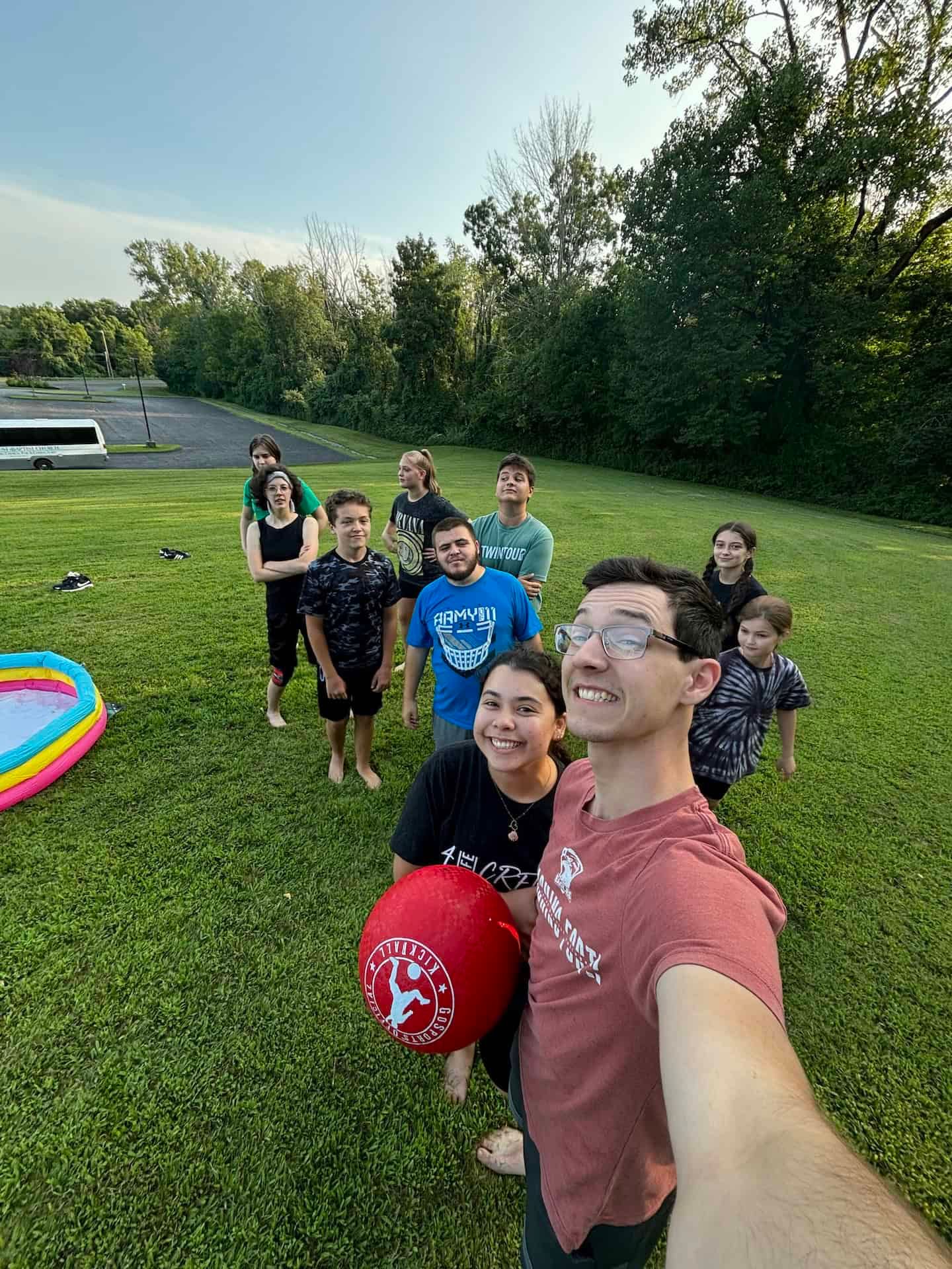 A group of people are standing in a grassy field holding balloons.