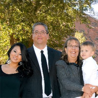 A family is posing for a picture in front of a tree.