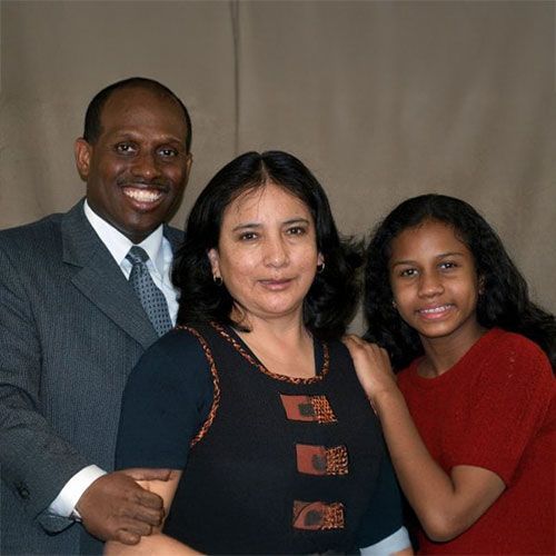 A man in a suit and tie poses with two women and a young girl