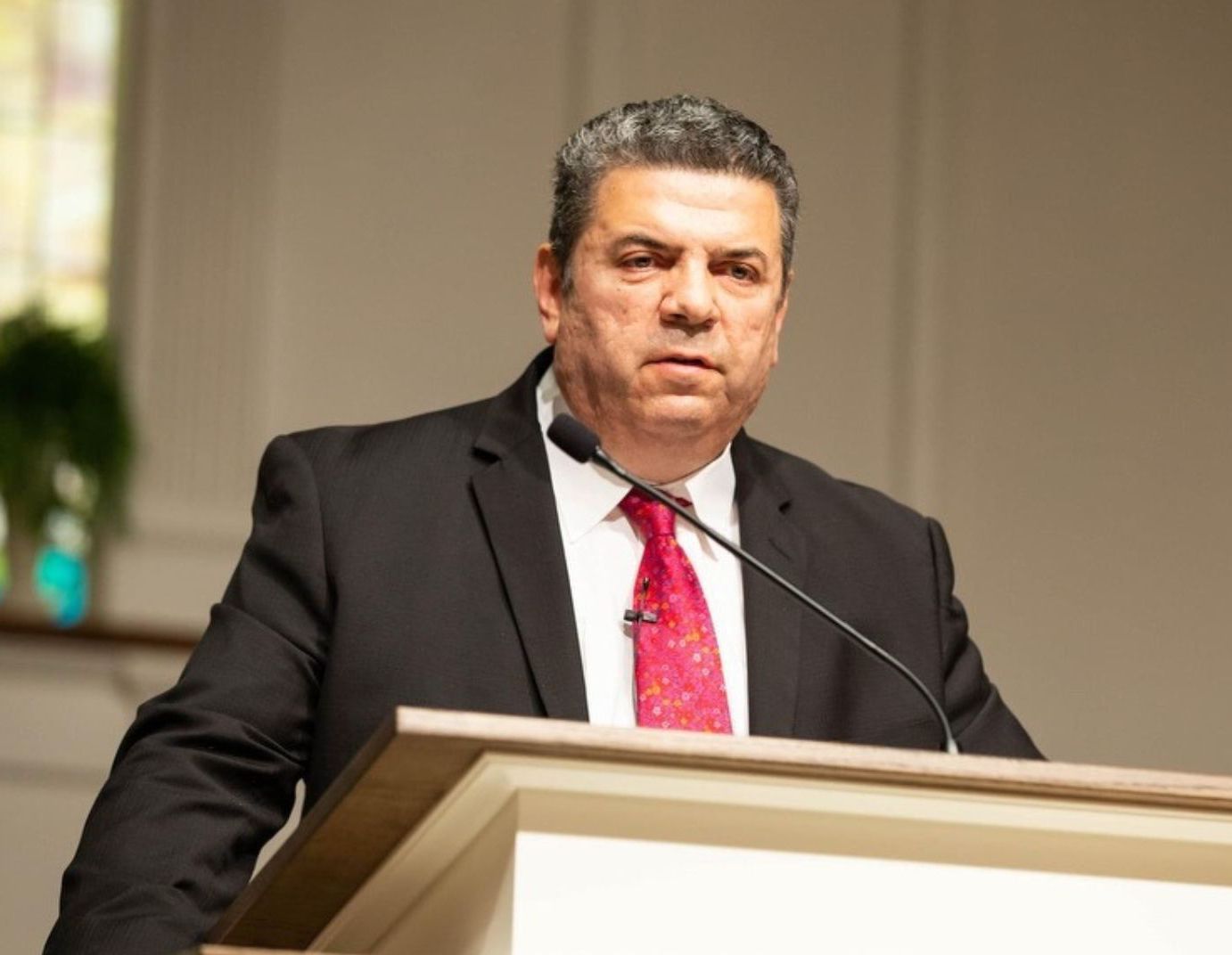 A man in a suit and red tie is sitting in a chair.