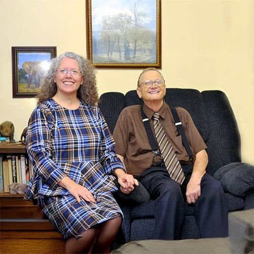 A man and a woman are sitting on a couch holding hands