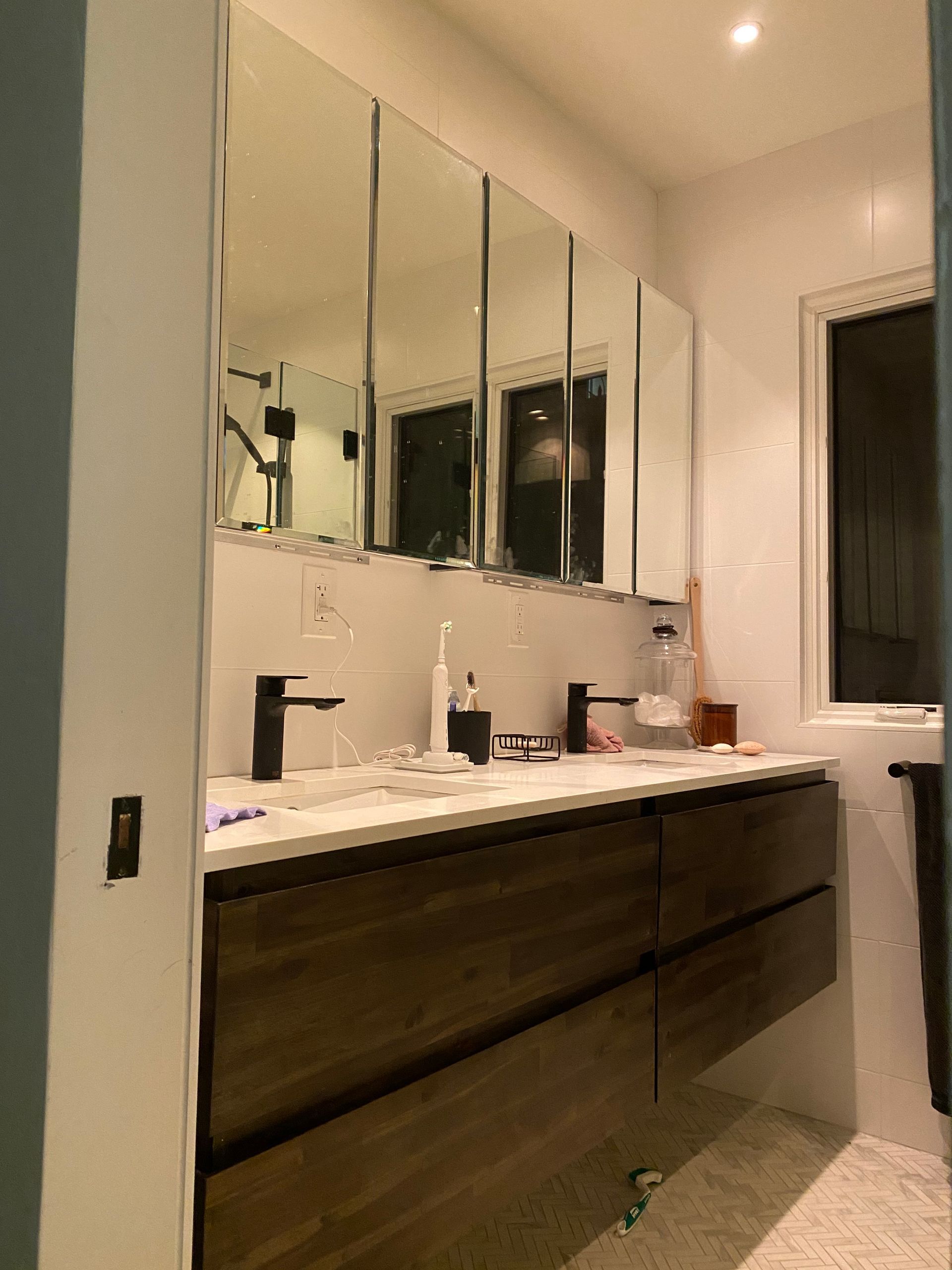 A bathroom with two sinks , mirrors and a window.
