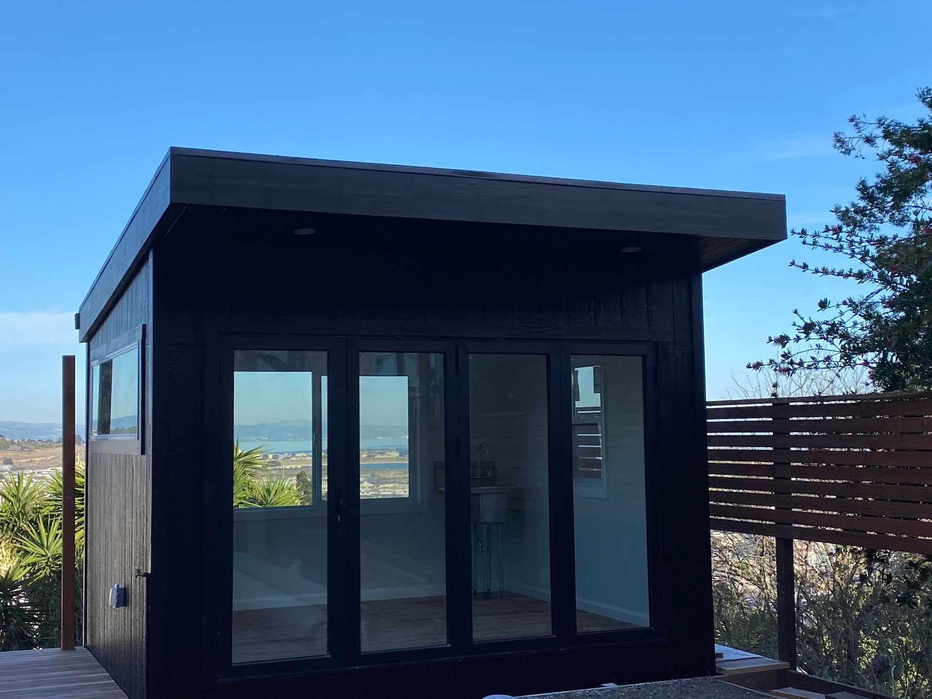 A small black building with a lot of windows and doors.