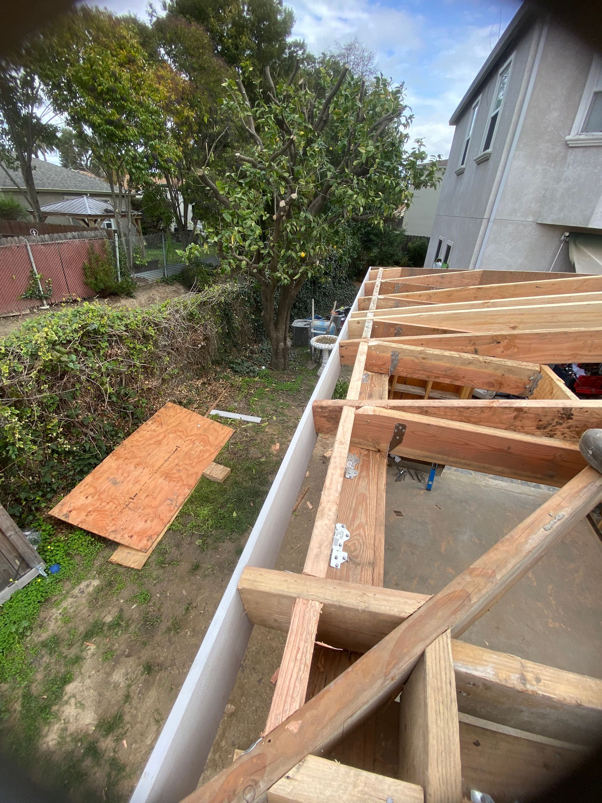 A wooden structure is being built in the backyard of a house.