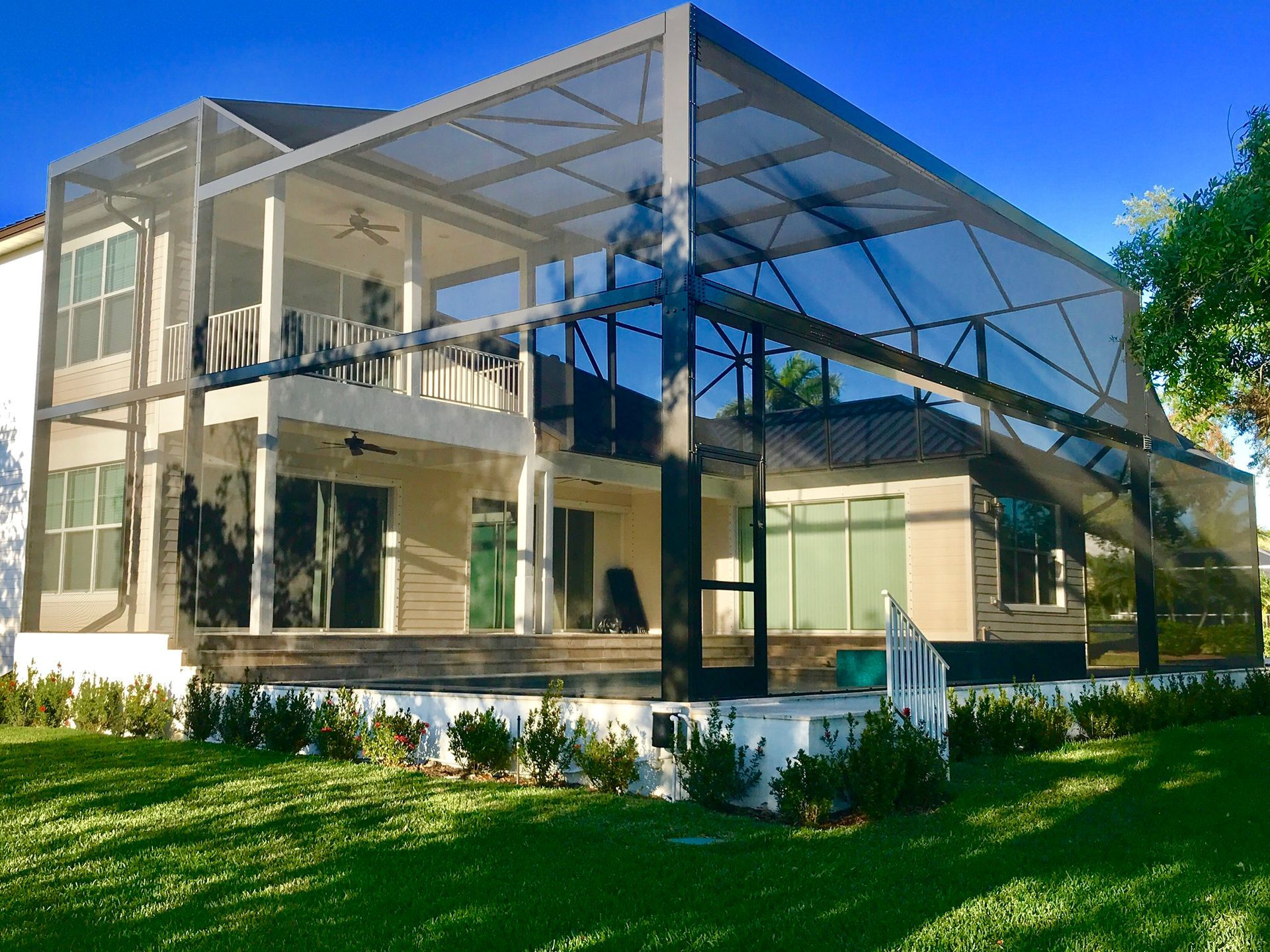 Screened porch with dark wood frame and ceiling, overlooking lush green trees.