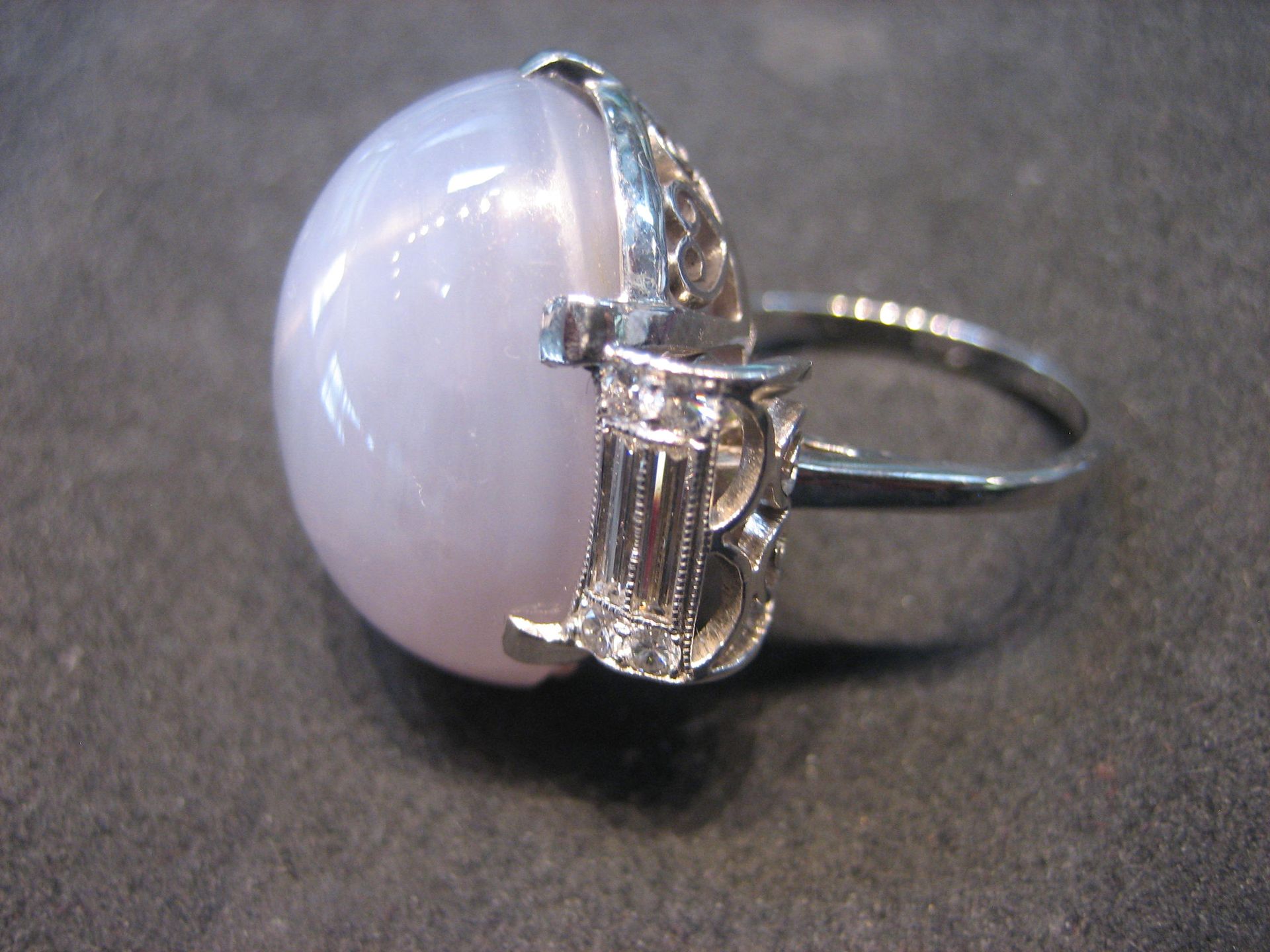 Ring with large, oval, pale pink stone, set in silver with decorative details.