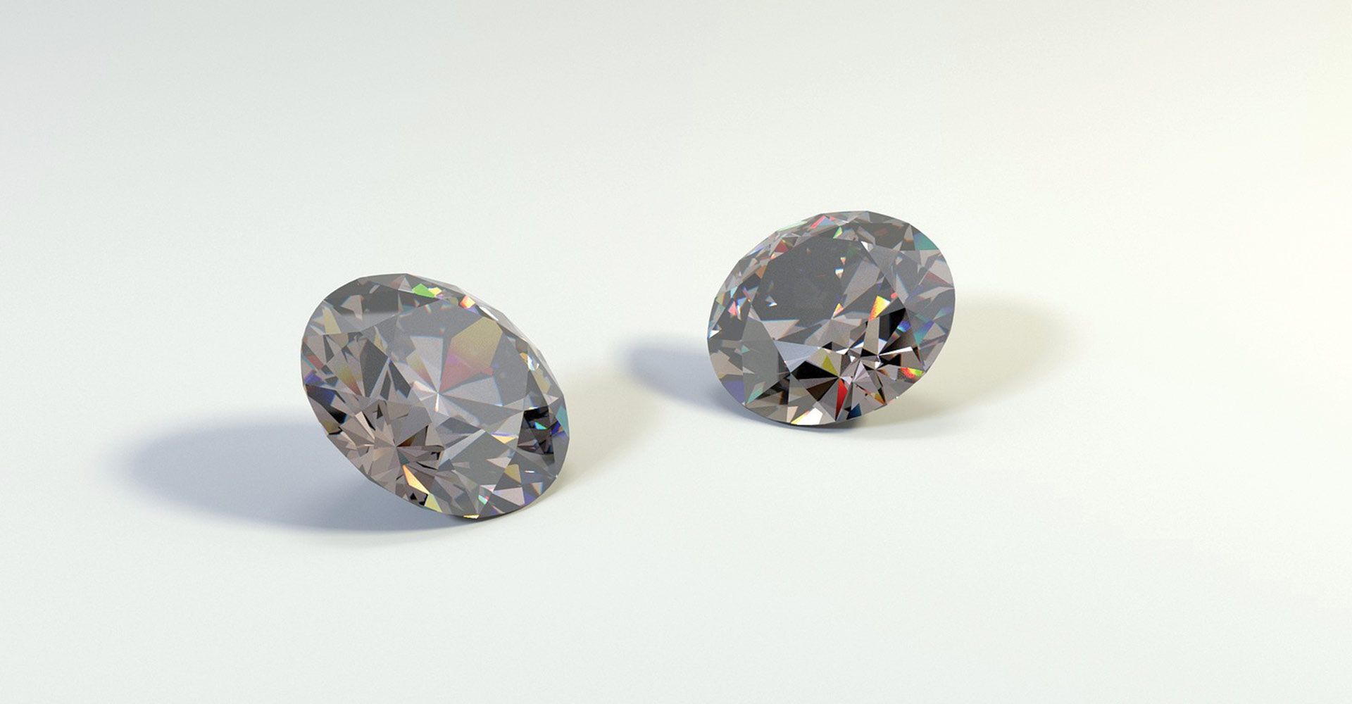 Two oval-cut gemstones reflecting light, resting on a white surface.