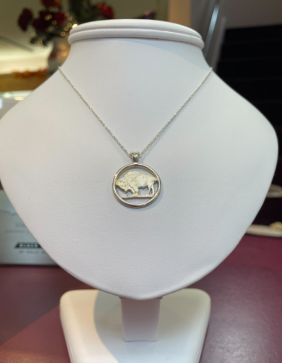 Silver necklace with a bison pendant displayed on a white jewelry bust.