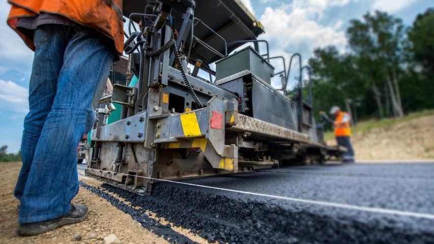 Road paving: workers with asphalt machine laying new road.