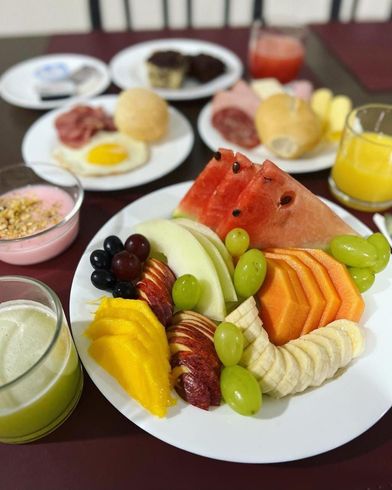 Um prato de frutas está sobre uma mesa com outros pratos de comida