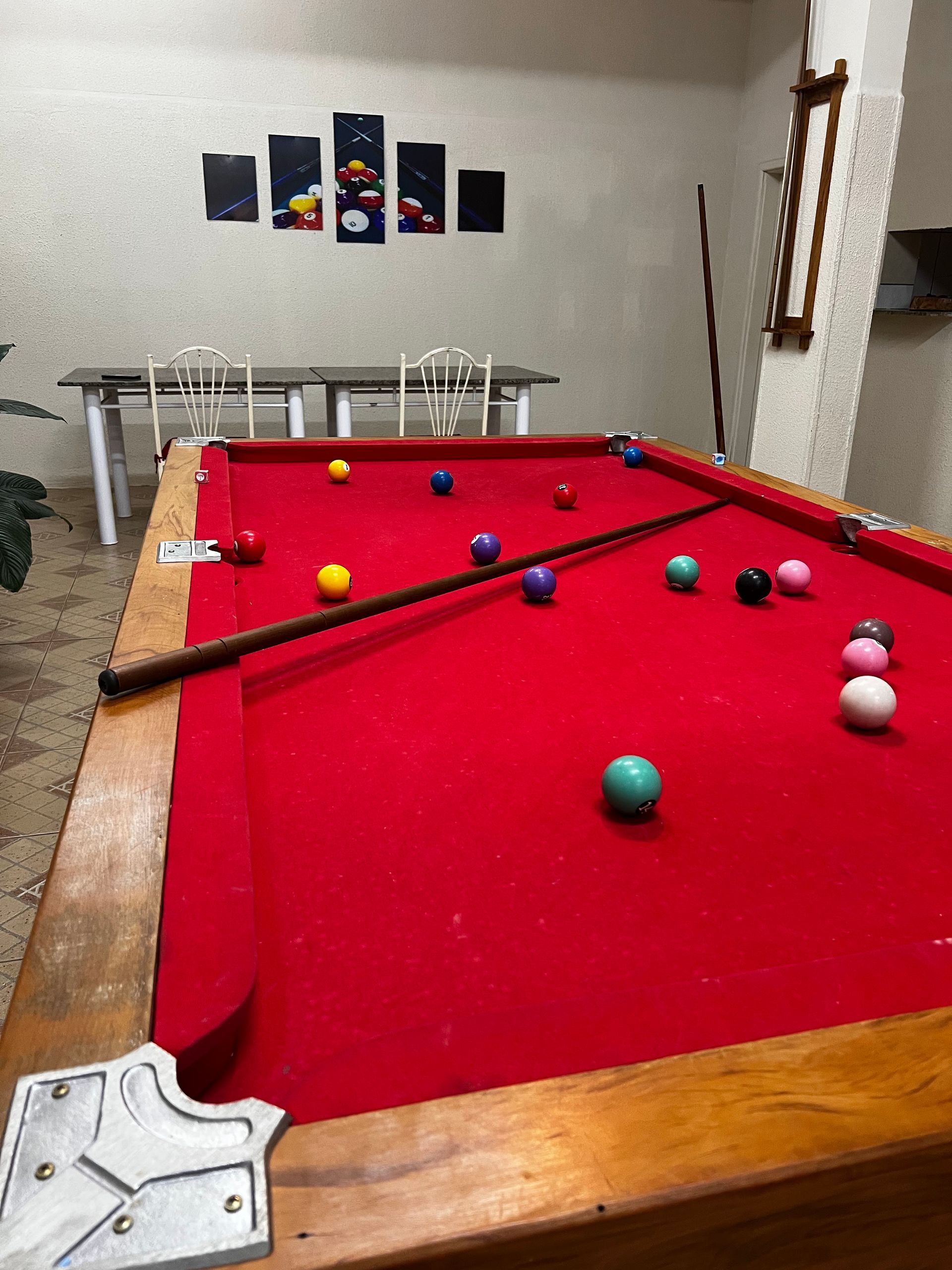 Uma mesa de sinuca com pano vermelho e bolas em uma sala