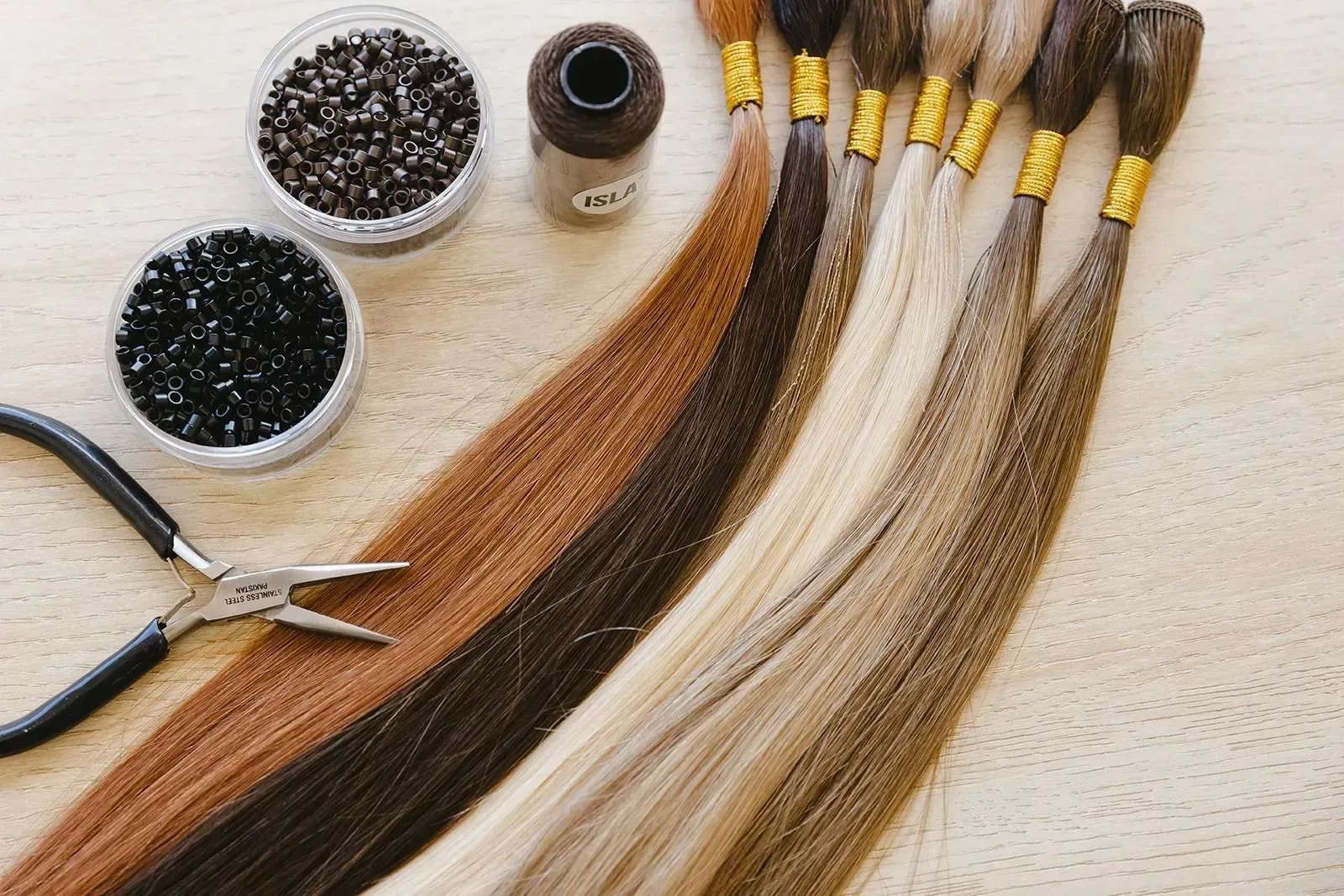 Hair extensions with beads and tools, various shades of brown and blonde.
