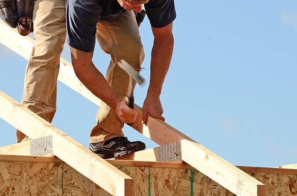 A man is working on a wooden roof with a hammer.