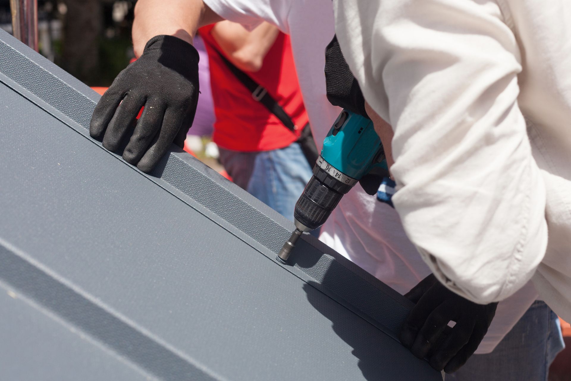 A man is working on a roof with a drill.