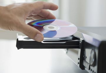 CD's - Edinburgh, UK - Overstocks Worldwide - CD stock A person is putting a cd into a cd player.