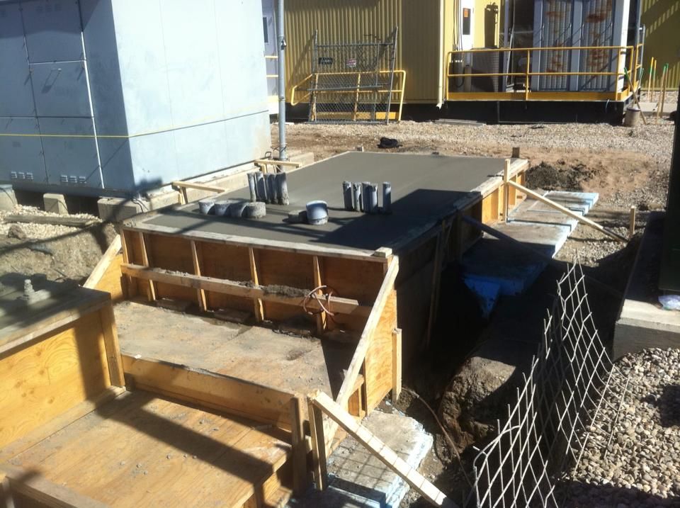 Wooden forms and freshly poured concrete for a utility structure, outdoors.