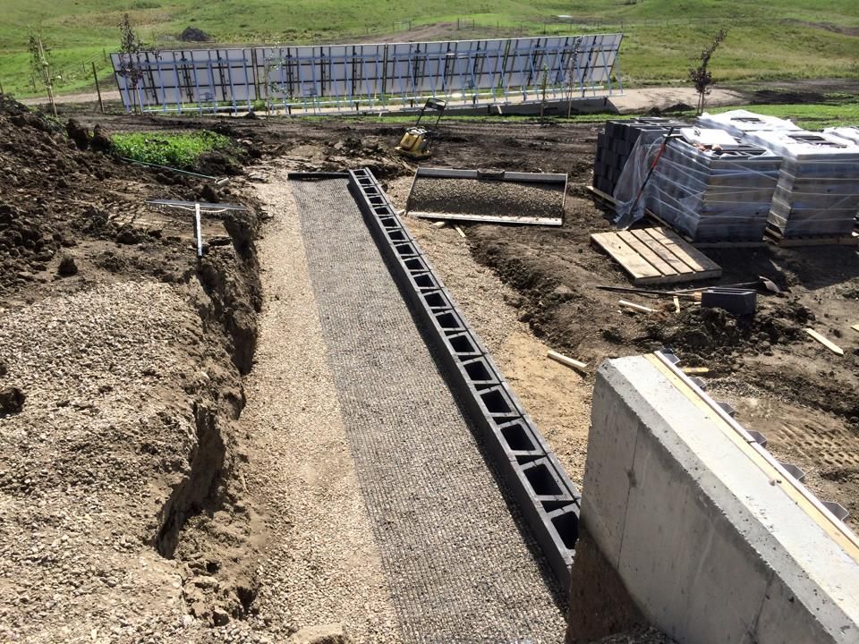Construction site with a trench filled with gravel and drainage system.