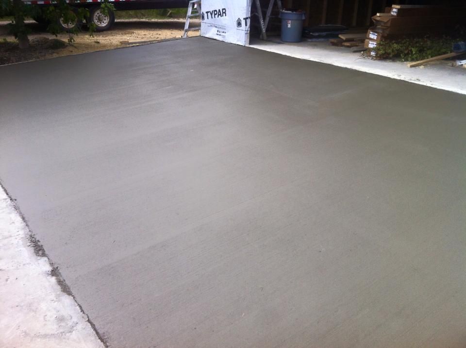 Freshly poured, gray concrete slab in an outdoor setting.