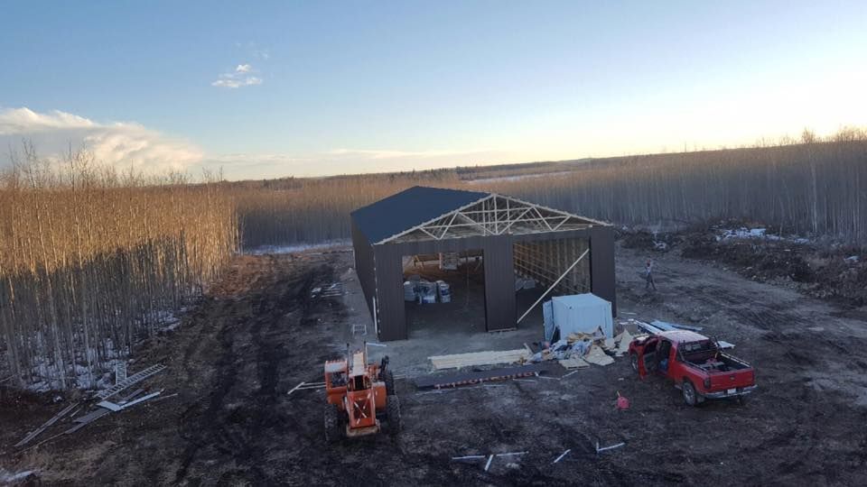 Construction site: brown metal-sided shed with dark roof.