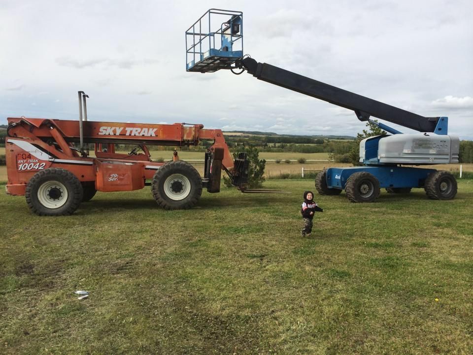 Orange Sky Trak and blue lift, child running on grass field, cloudy sky in background.
