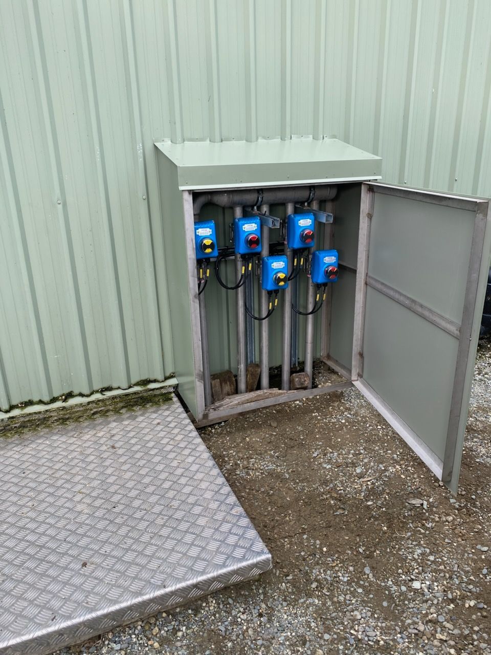 Gray metal box with open door revealing six blue control units with attached black wires.