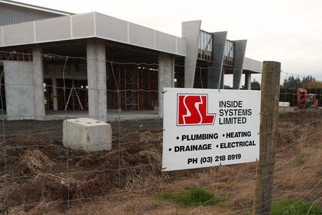 Construction site with a sign for Inside Systems Limited offering plumbing, heating, drainage, and electrical services.