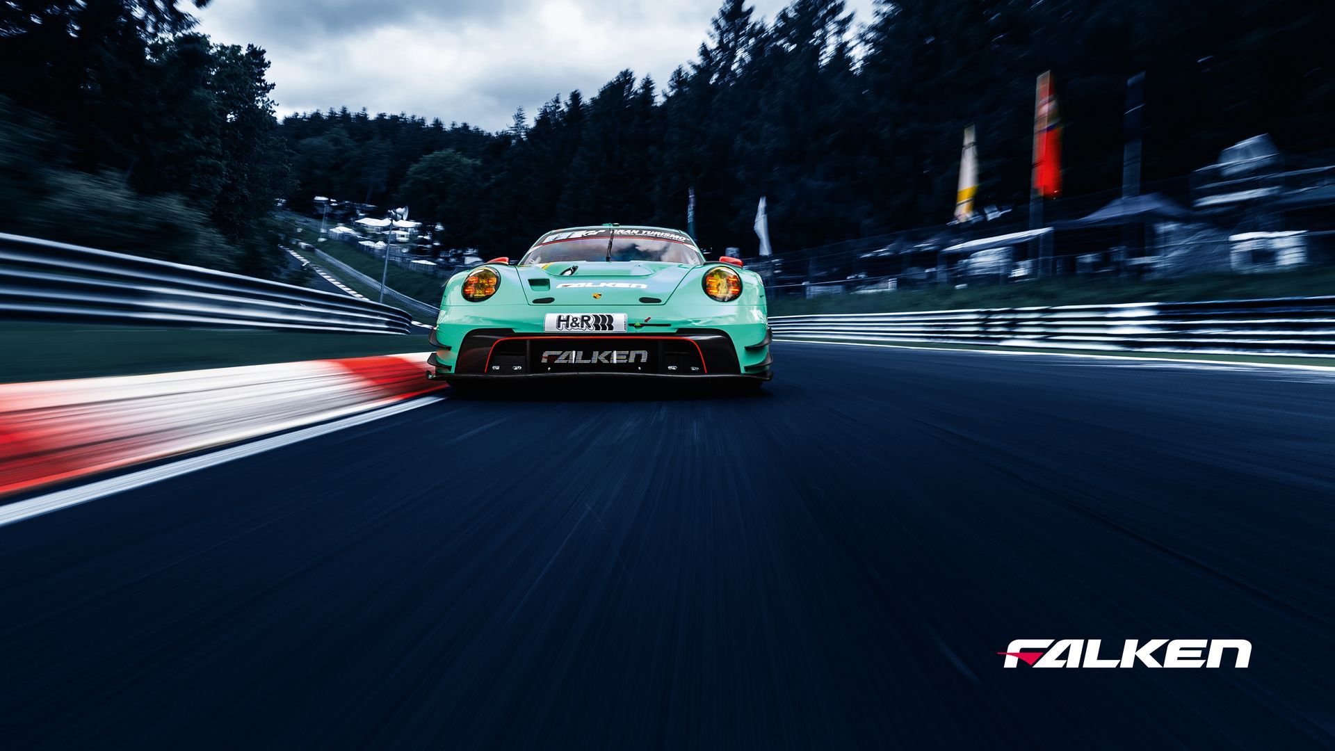 Hands in bright orange gloves hold an automotive diagnostic scan tool with glowing indicator lights on a dark surface.