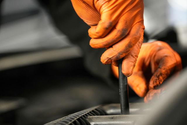 Close up of hands with orange gloves working on a car 