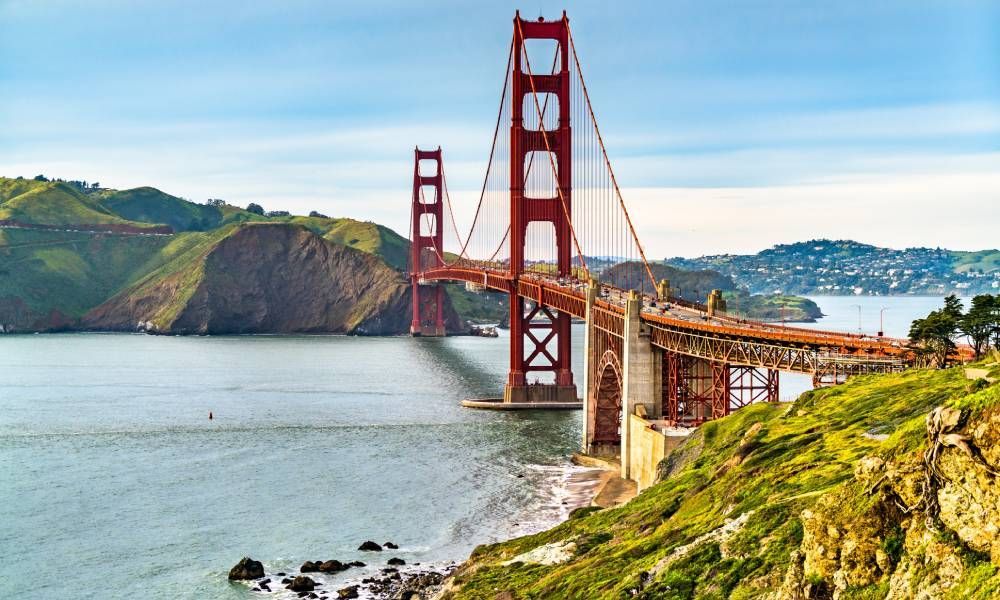 The Golden Gate Bridge with a backdrop of San Francisco nature and hills and the skyline on a cloudy day