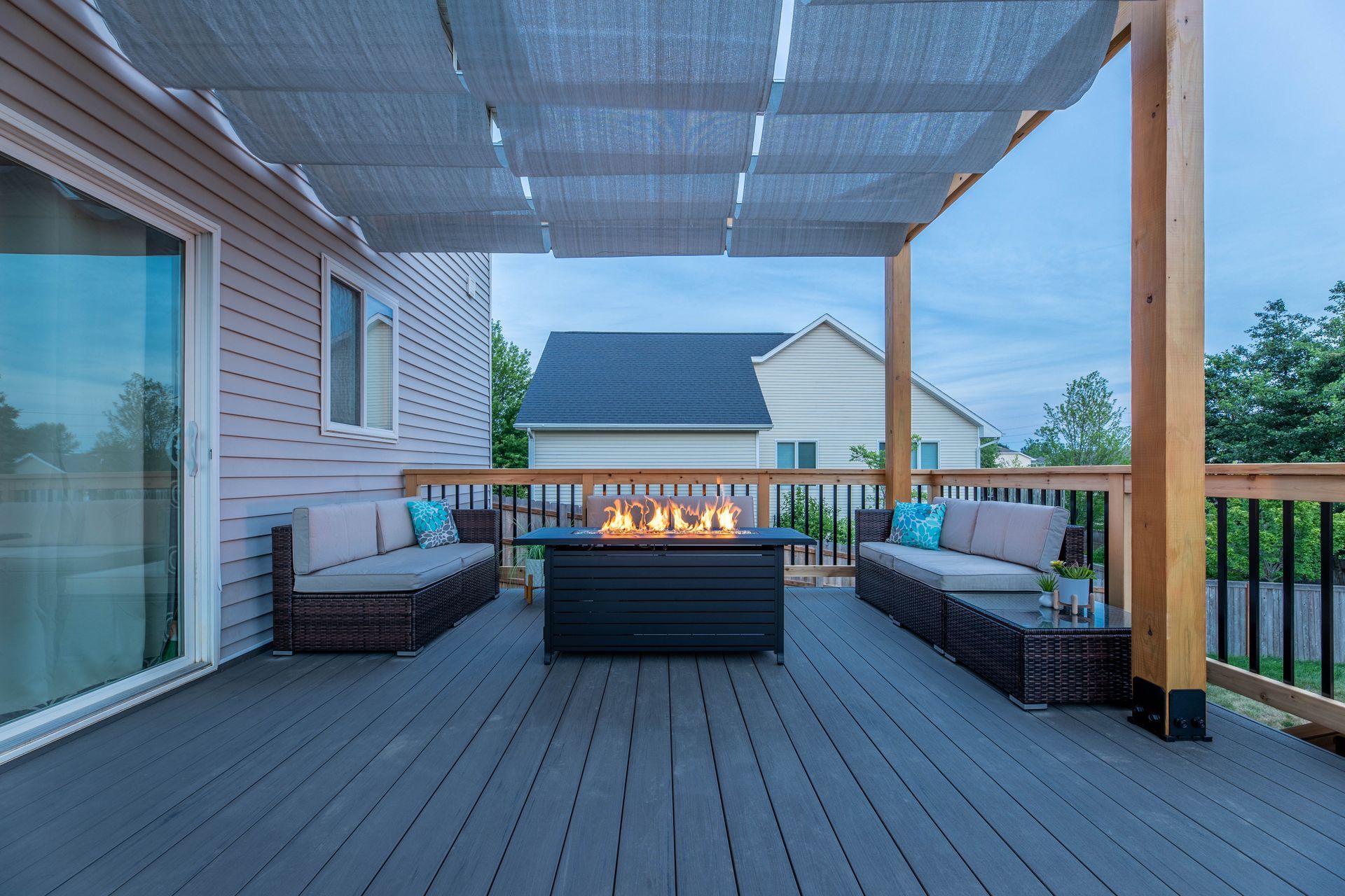 A deck with a fire pit and couch under a canopy.