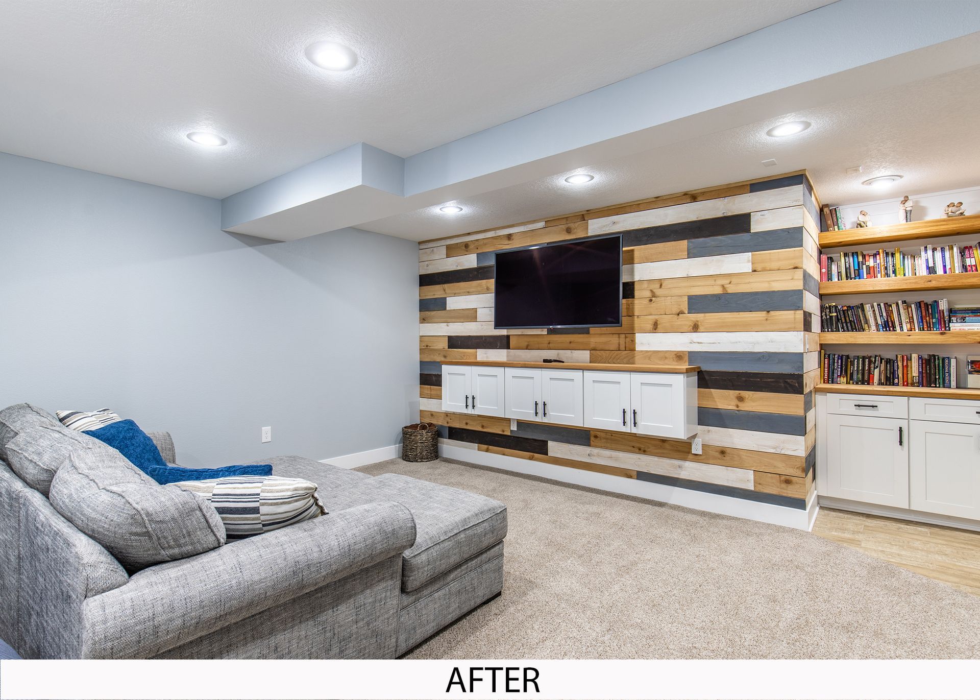 A living room in a basement with a wooden wall and a flat screen tv.