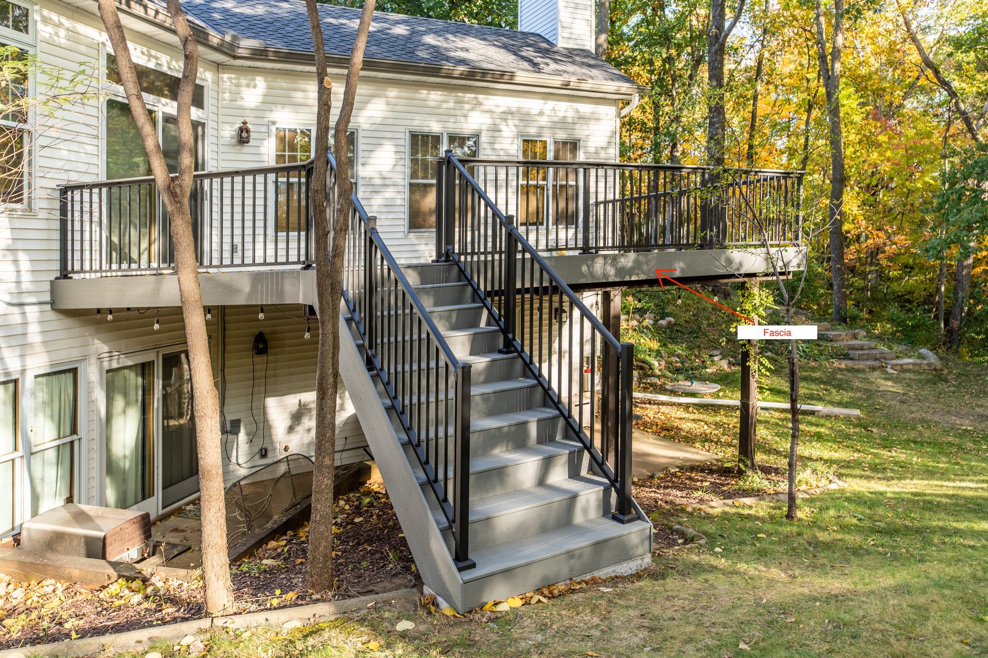 A white house with a deck and stairs leading up to it.