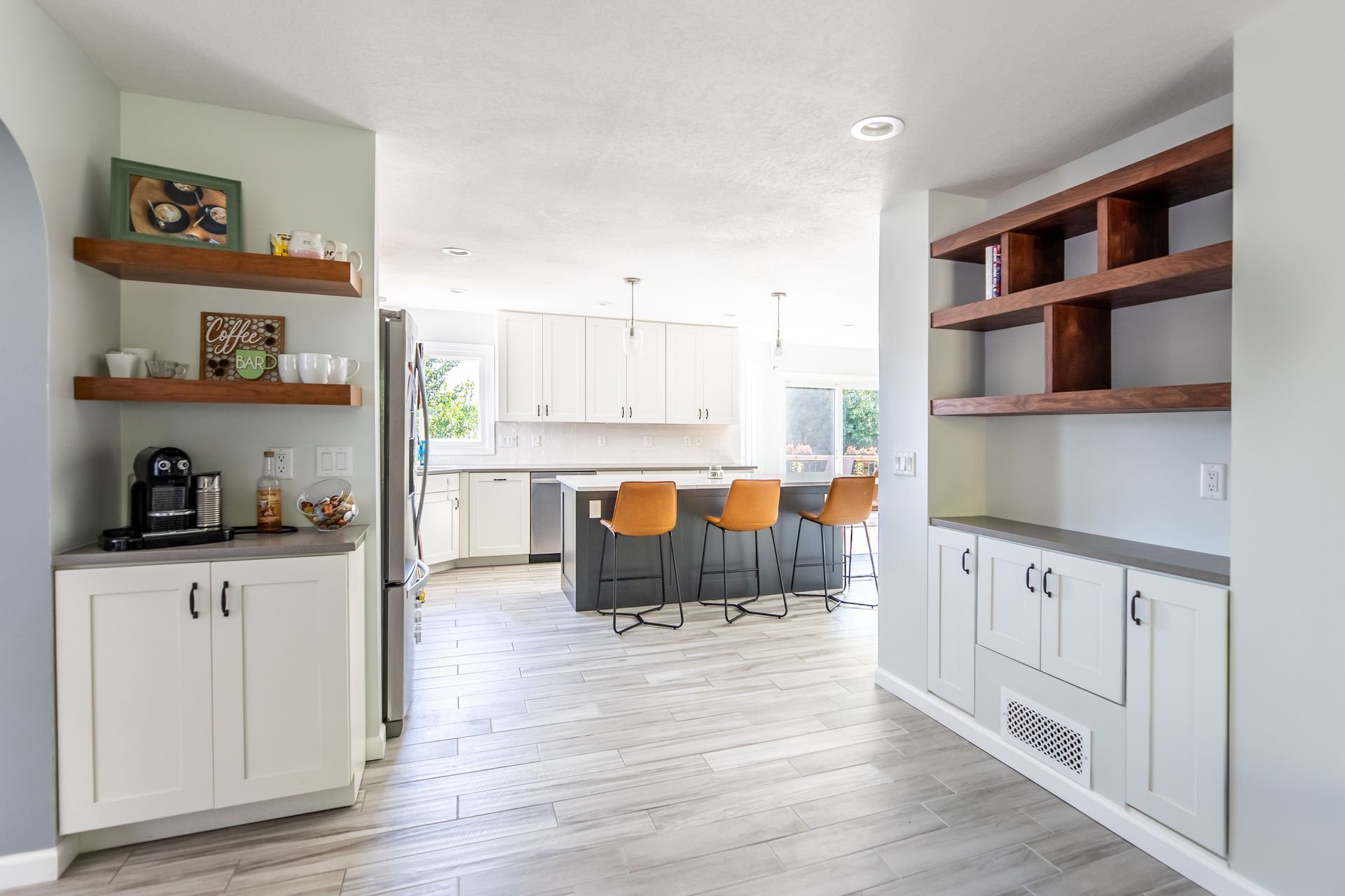 A kitchen with white cabinets and wooden shelves.