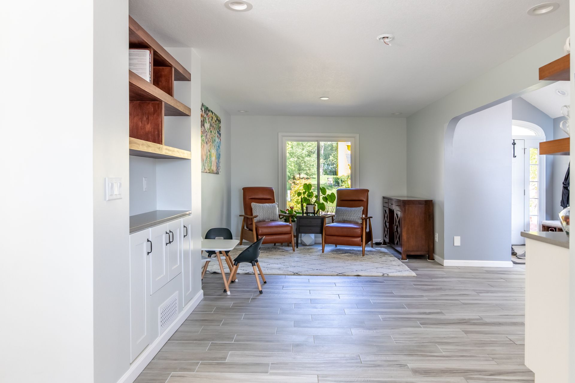 A living room with hardwood floors , two chairs , a table and a window.