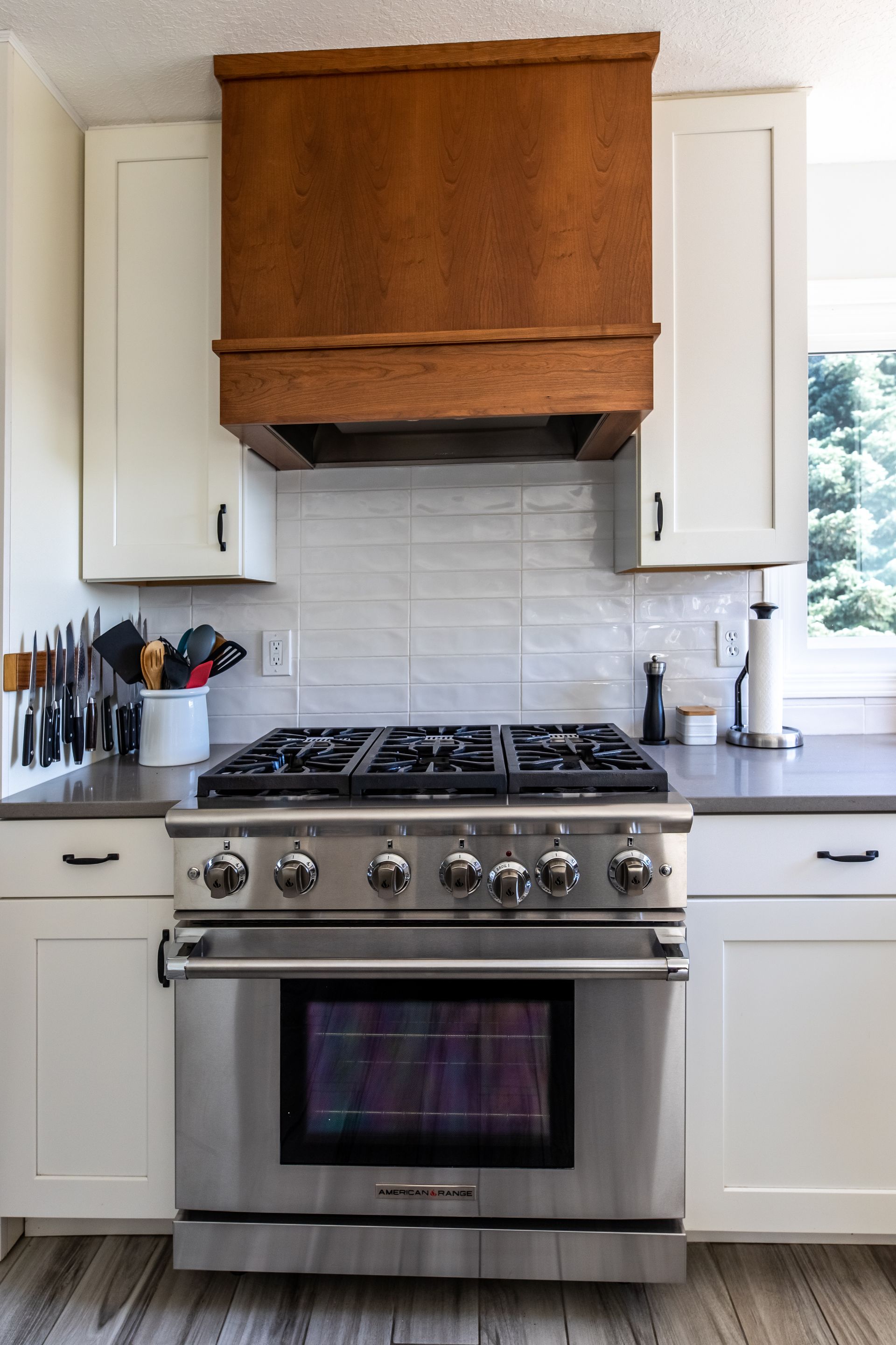 A kitchen with a stove and oven with a wooden hood above it.