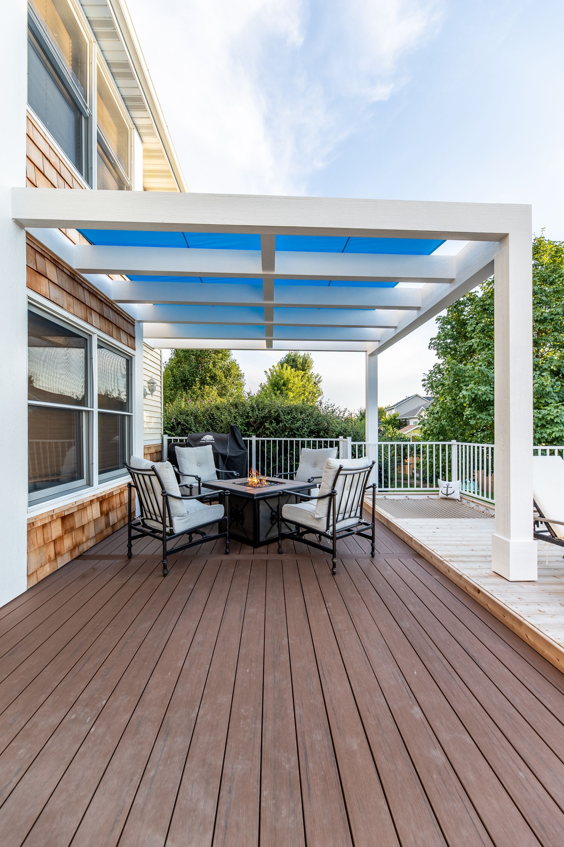 A wooden deck with a table and chairs under a pergola.