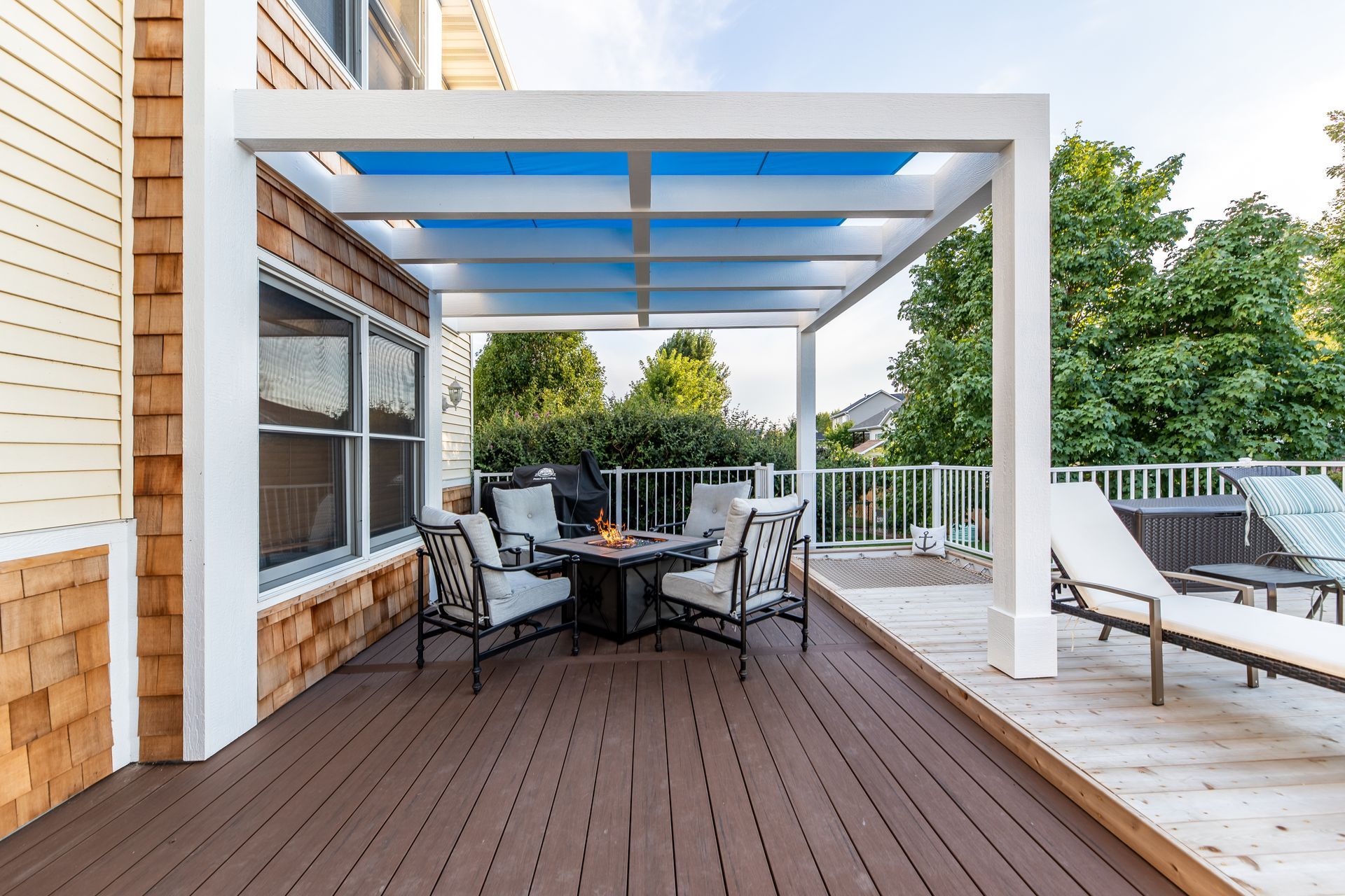 A deck with a table and chairs under a pergola.