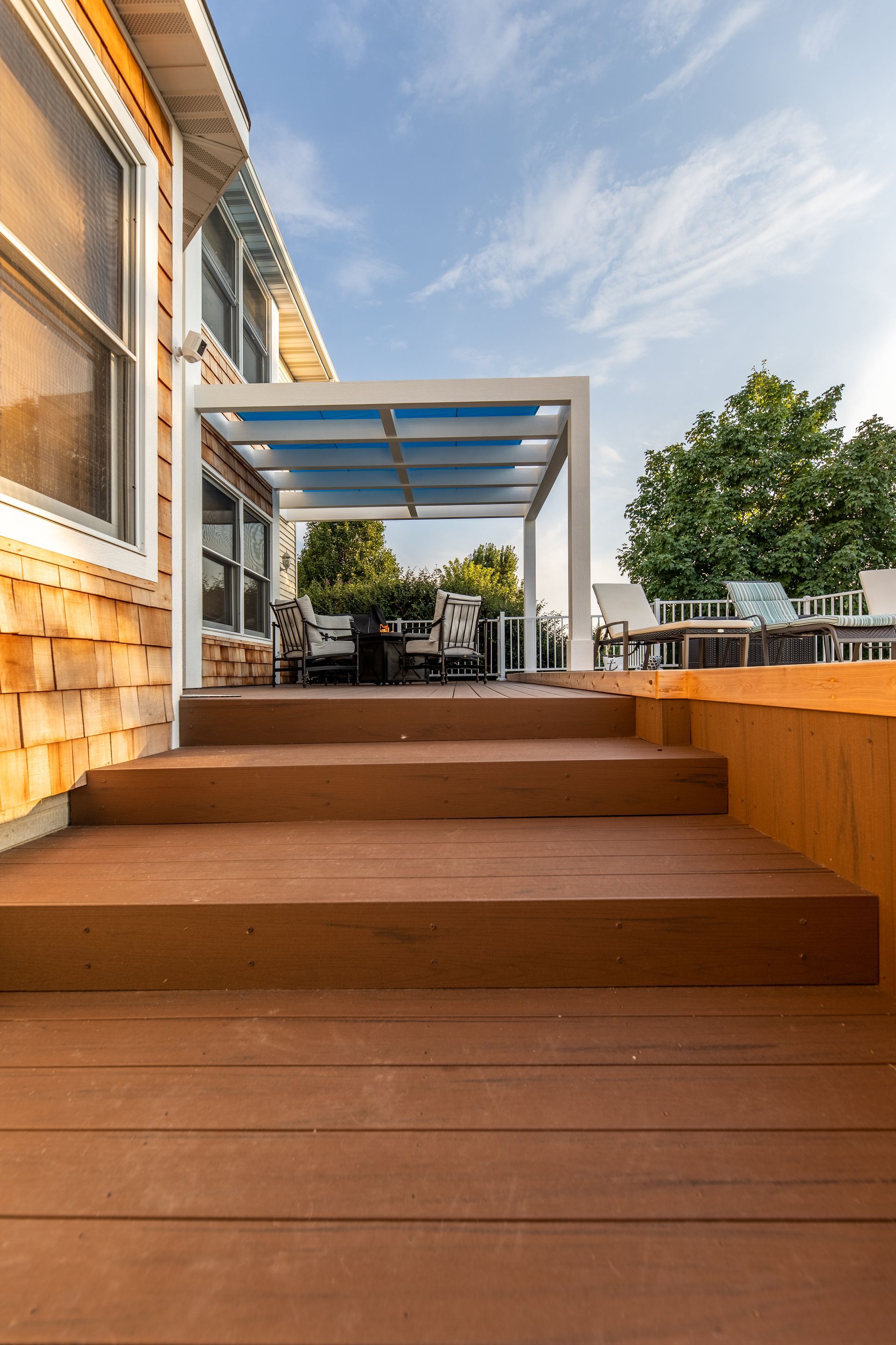 A wooden deck with stairs leading up to it and a pergola.