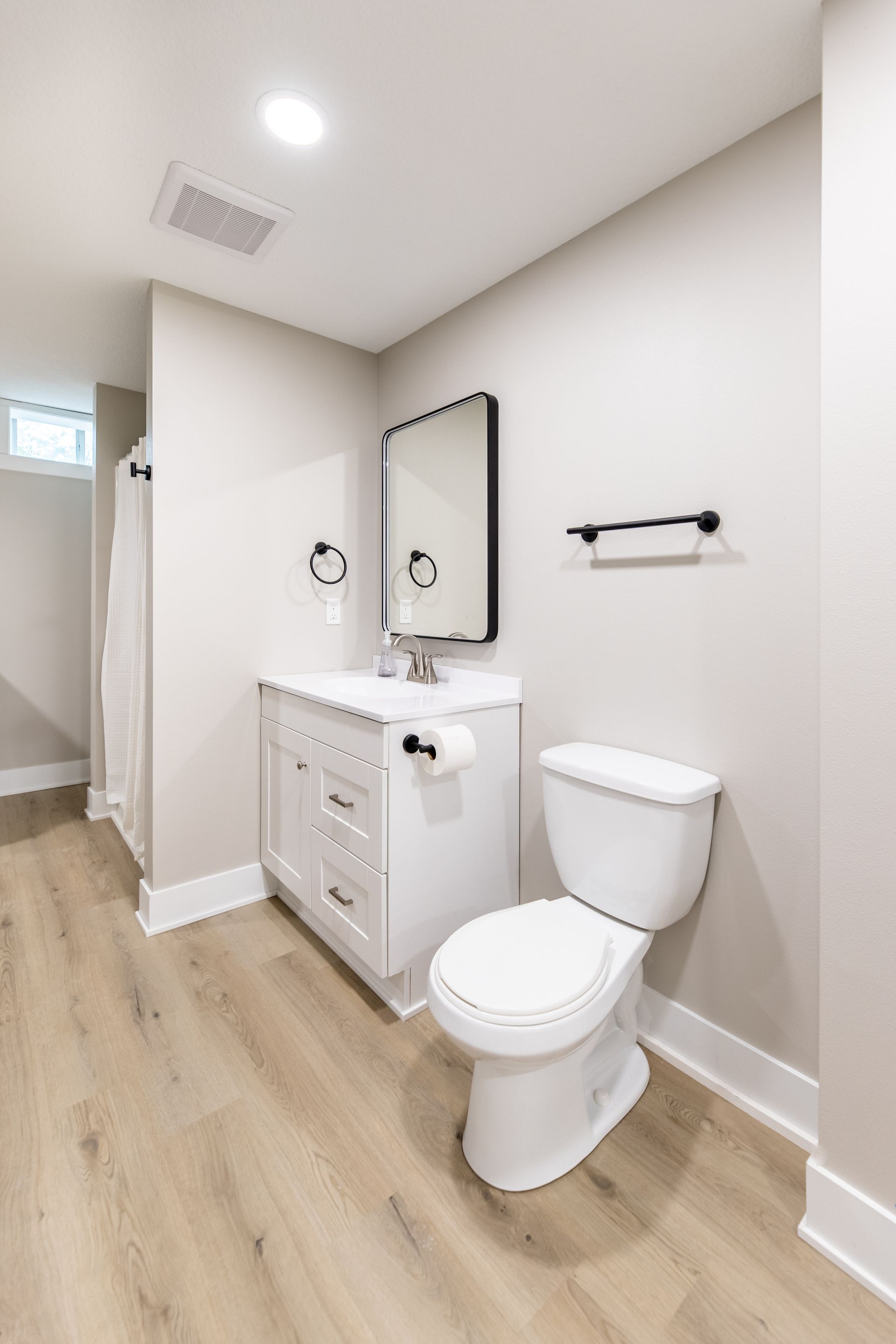 A bathroom with a toilet , sink and mirror.