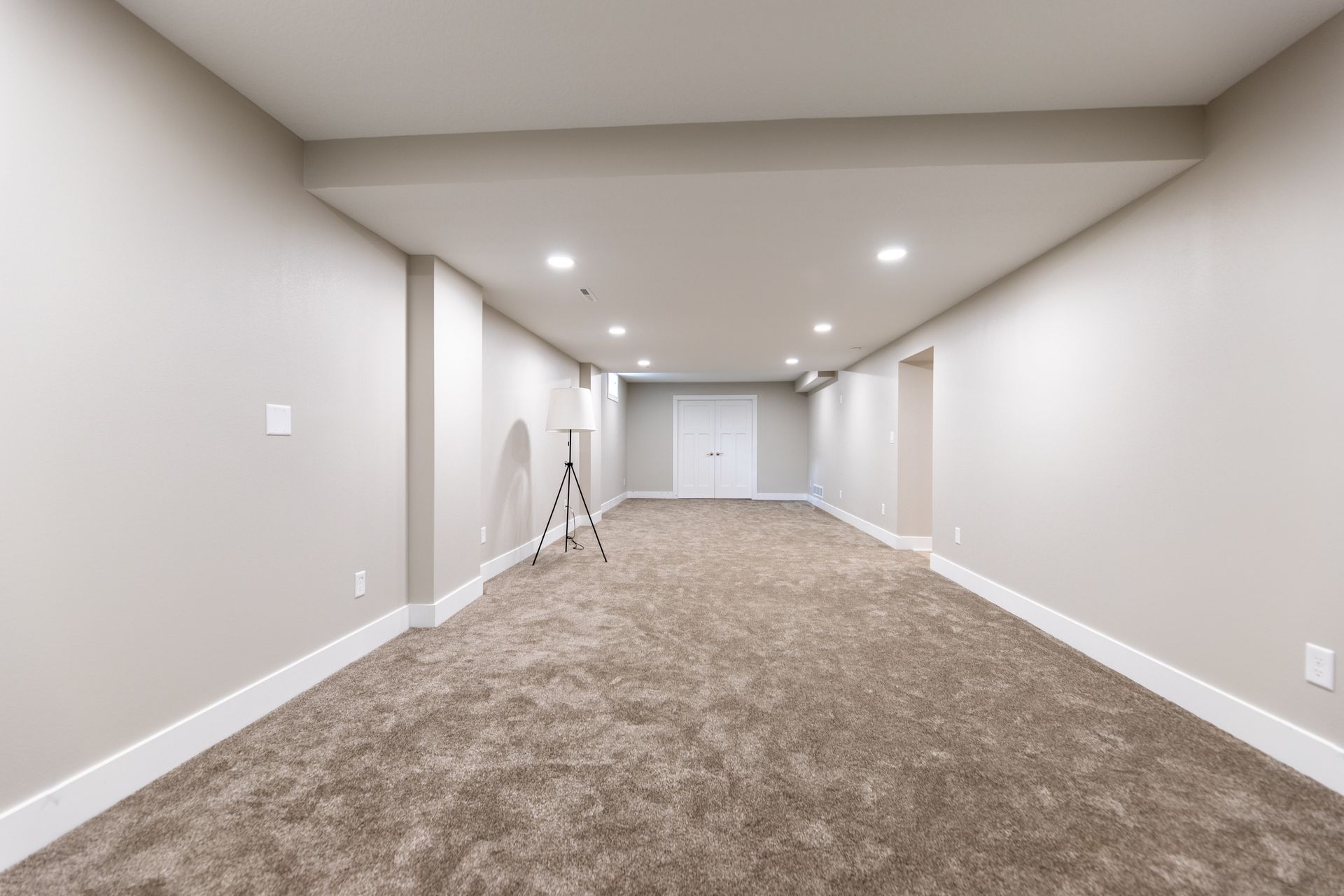 An empty basement with a tripod in the middle of it.