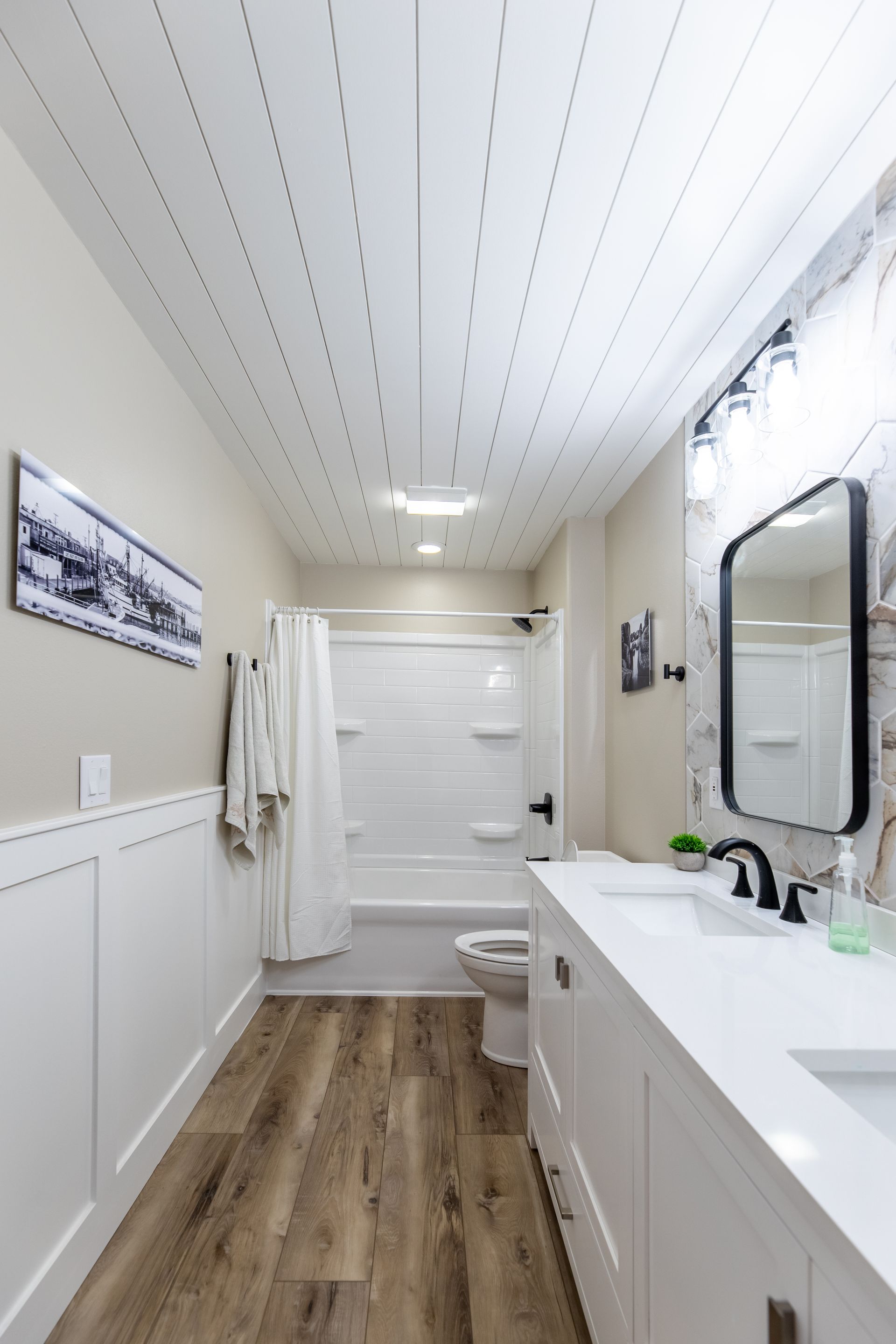 A bathroom with a sink , toilet , shower and mirror.