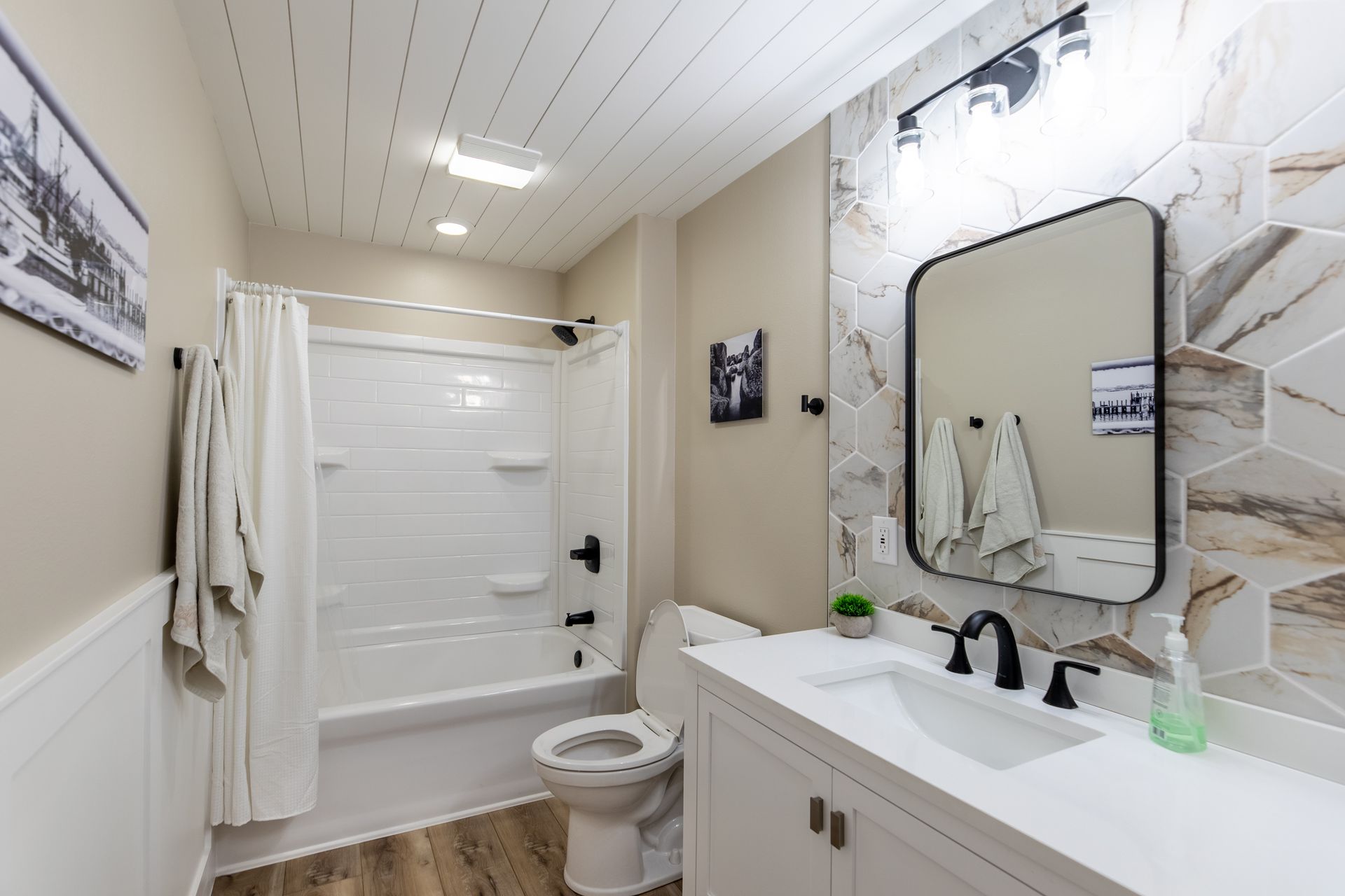 A bathroom with a toilet , sink , shower and mirror.