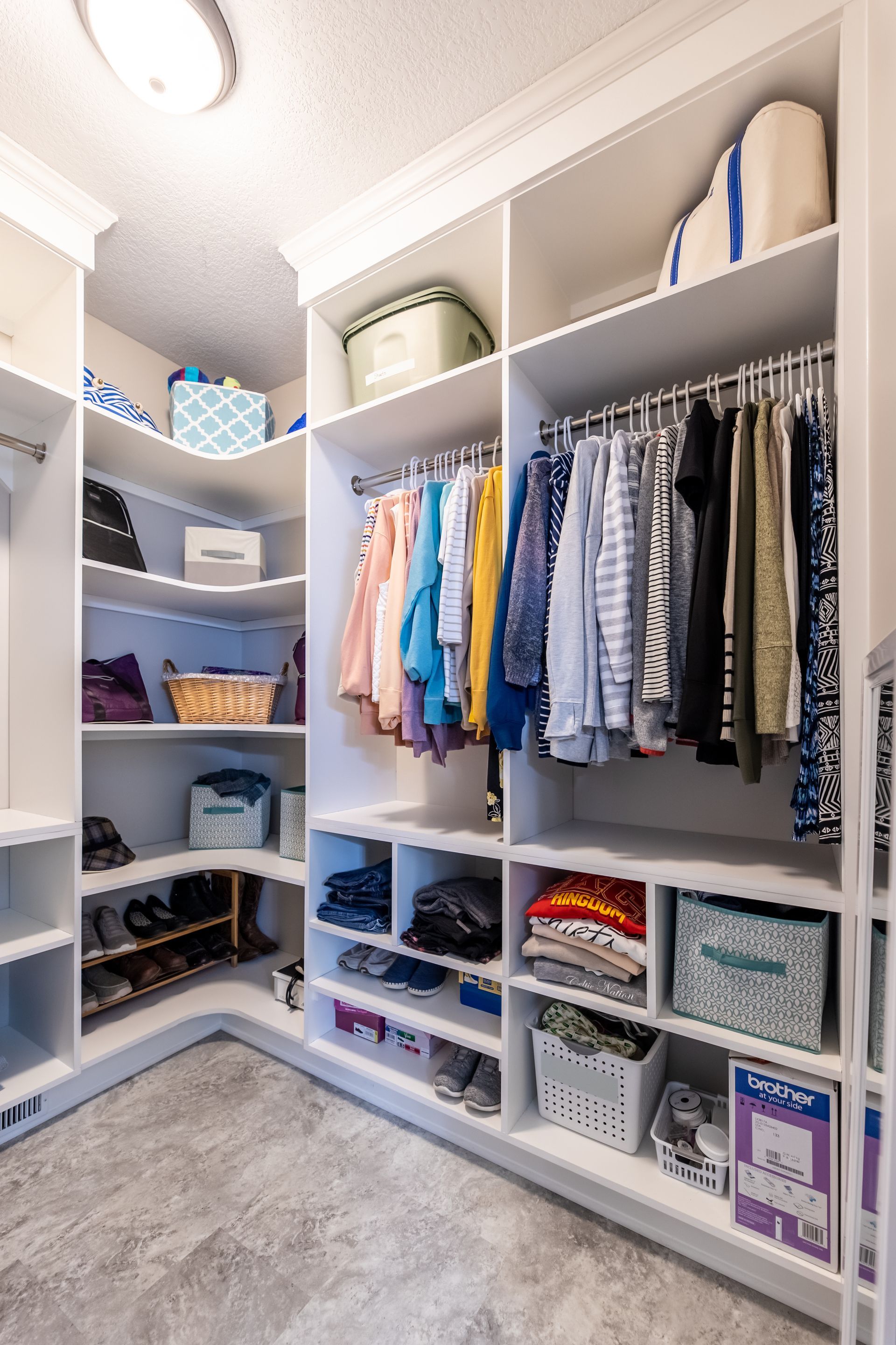 A custom remodeled walk in closet filled with lots of clothes and shoes.