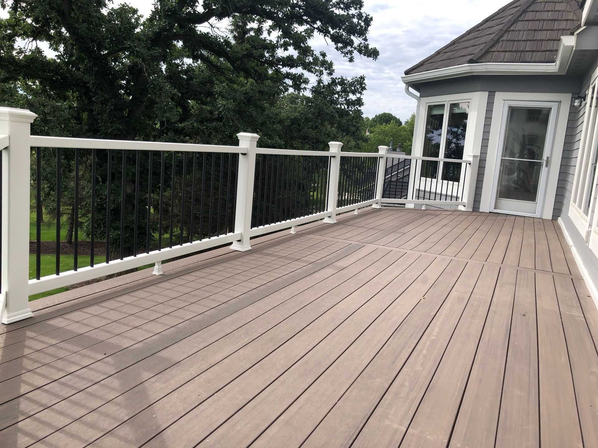 A large deck with a white railing and a sliding glass door.