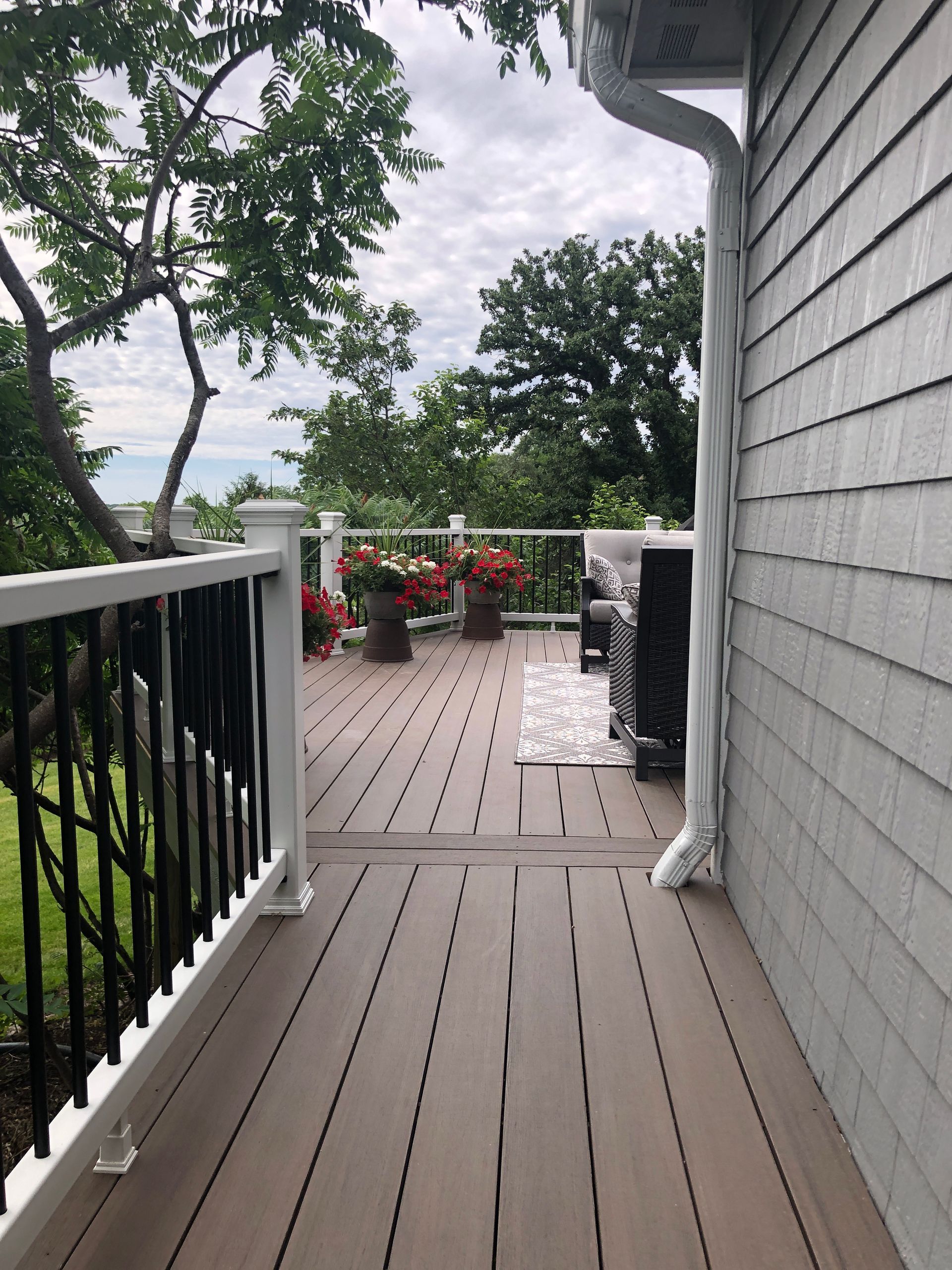 A wooden deck with a white railing and flowers on it