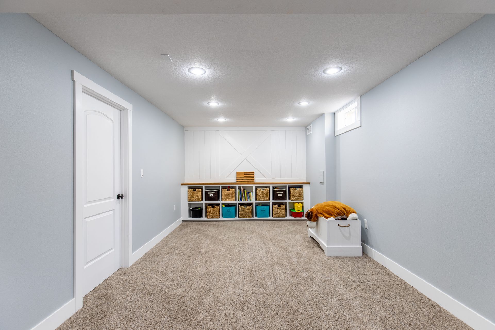 An empty basement with a shelf and baskets on the wall.